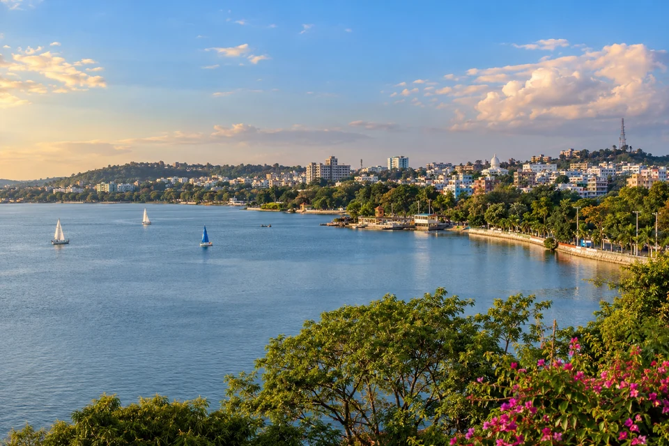Illustration: Illustrative city view of Upper Lake waterfront with greenery and Bhopal city backdrop